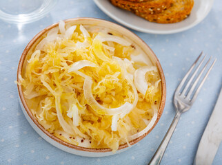 Homemade pickled cabbage with fresh onion on bowl, natural probiotic. Popular Russian dish