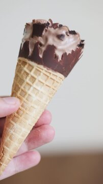 Close-up of a man holding a chocolate cornetto ice cream
