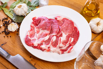 Raw pork neck on the kitchen table along with other ingredients for making a delicious lunch or dinner