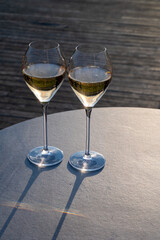 Glasses of white sparkling wine brut, grand reserve, champagne on green hilly vineyards in old wine making grand cru Ay-Champagne village in Vallee de la Marne, Champagne, France