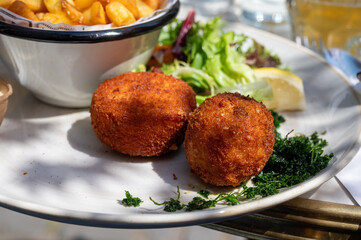 Lunch in cafe with vegetarian cheese and green asparagus croquettes served with fresh salad and french fries potato in Bruges, Belgium