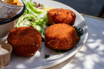 Lunch in cafe with vegetarian cheese and green asparagus croquettes served with fresh salad and french fries potato in Bruges, Belgium
