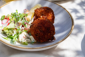 Lunch in cafe with vegetarian cheese and green asparagus croquettes served with fresh salad and french fries potato in Bruges, Belgium