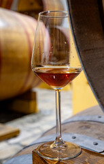 Visit of wine cellar with old large oak barrels, glass of fortified dry or sweet tasty marsala wine from barrels in Marsala, Sicily, Italy