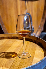 Visit of wine cellar with old large oak barrels, glass of fortified dry or sweet tasty marsala wine from barrels in Marsala, Sicily, Italy