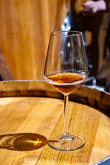 Visit of wine cellar with old large oak barrels, glass of fortified dry or sweet tasty marsala wine from barrels in Marsala, Sicily, Italy