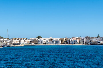 Obraz premium Boat trip and view on coastline of Favignana island with small village, shallow bays with clear turquoise water, tuff rocks, abandoned quarries, caves, Egadi Islands near Sicily, Italy