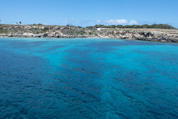 Boat trip and view on coastline of Favignana island with shallow bays with clear turquoise water, tuff rocks, abandoned quarries, caves, Egadi Islands near Sicily, Italy