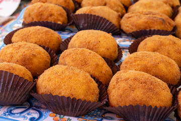 Arancini Sicilian, deep-fried rice balls made with risotto, filled with ingredients mozzarella, ragu, peas, coated in breadcrumbs fried to crispy, brown on market in Palermo, Sicily