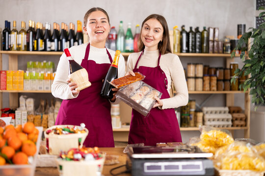 Smiling sellers introduce customers to new high-quality products. Sellers offer wine, champagne and sweets. Delicious food, snacks and alcohol for the holiday