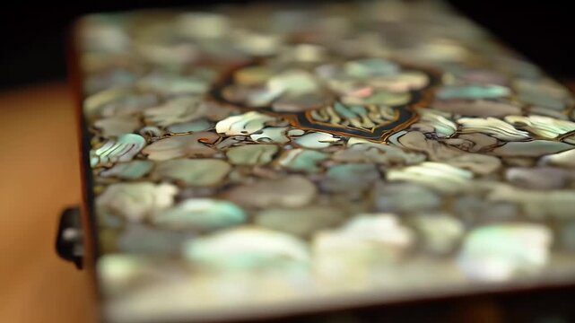 Close-up of a mother of pearl inlay pattern on a decorative object, showcasing iridescent shell fragments.