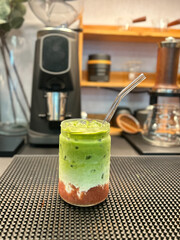 Strawberry Matcha Latte served in a plastic cup on a trendy coffee shop background.