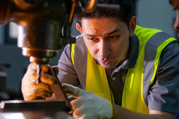 Skilled worker focused on operating machinery in a factory. Wearing high visibility vest and gloves, demonstrating precision, technical ability, safety, and industrial expertise.