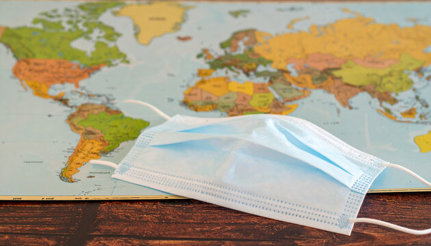 World Map and Face Mask: A poignant image of a surgical face mask resting on a detailed world map.