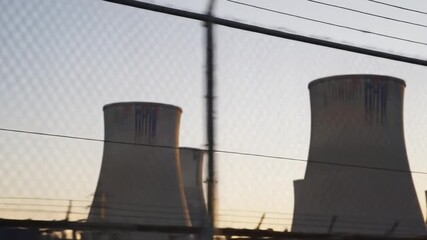 Dynamic DriveBy View of a Power Plants Cooling Towers Against a Sunset Sky.