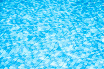 Vibrant blue checkered swimming pool water with shimmering light reflections and ripples, ideal for summer backgrounds and abstract textures.
