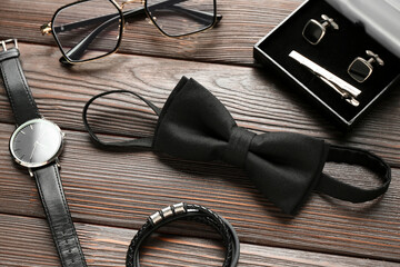 Set of stylish male accessories with bow tie on wooden background, closeup