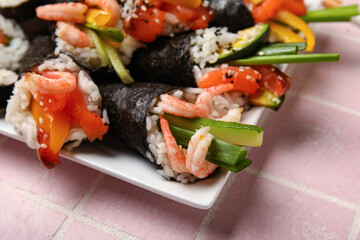 Plate with tasty sushi cones on color tile background, closeup