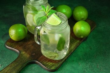 Mason jar of tasty mojito on green background