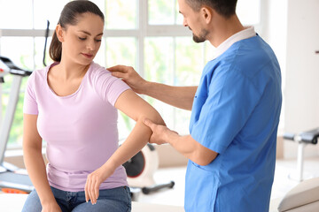 Fototapeta premium Male physiotherapist working with young woman in rehabilitation center