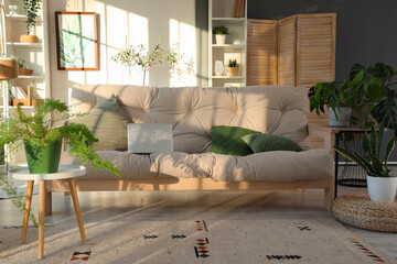 Interior of light living room with green plants, sofa and shelf units