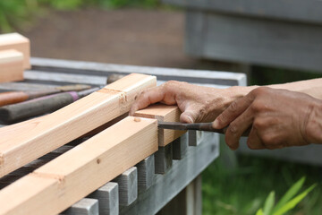 ノミで材木を削る男性