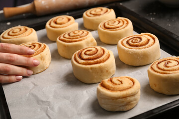 Woman preparing cinnamon rolls at table