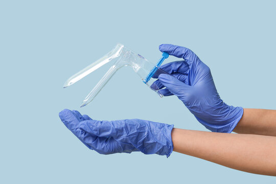 Doctor hands in medical gloves with gynecological speculum on blue background