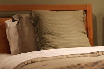 Cama de casal arrumada com travesseiros verdes e colcha branca macia, em quarto aconchegante de decora&ccedil;&atilde;o natural / Cozy double bed with green pillows and soft white bedspread in natural decorated bed