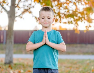  A young boy meditating in a park during autumn