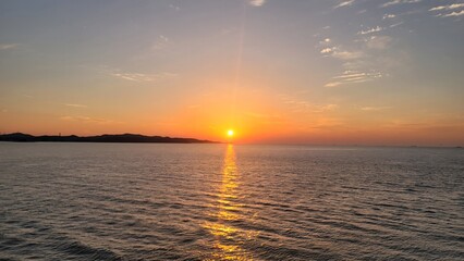 Naklejka premium Sunset over the Ocean Horizon with Orange Sky