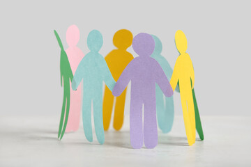 Paper human figures on white table. Inclusion concept