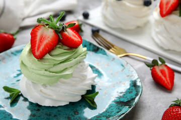 Plate of sweet Pavlova cake with fresh strawberries and mint on grey background, closeup