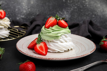 Plate of sweet Pavlova cakes with fresh strawberries on black background