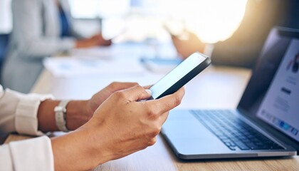 Business professional using a phone to text or email in an office, networking via a social media app. Close-up of hands with a laptop nearby as a secretary types on the mobile device for research.	
