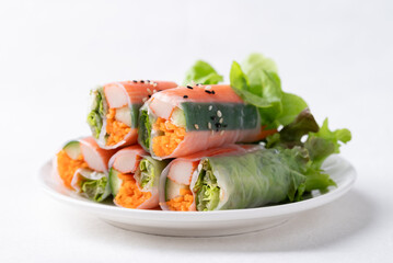 Salad roll with crab stick, carrot, cucumber and lettuce wrapped with rice paper on dish