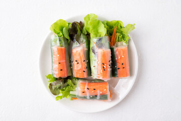 Top view of salad roll with crab stick, carrot, cucumber and lettuce wrapped with rice paper on dish with white background © nungning20