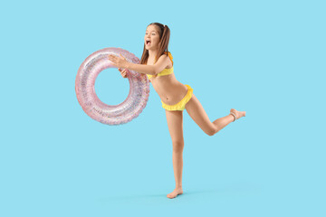 Fototapeta na wymiar Cute girl with swim ring on blue background