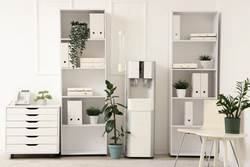 Shelving units with folders, houseplants and water cooler in office