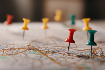 Close-up of colorful push pins marking locations on a map.