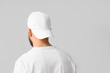 Handsome young man in stylish cap on grey background, back view