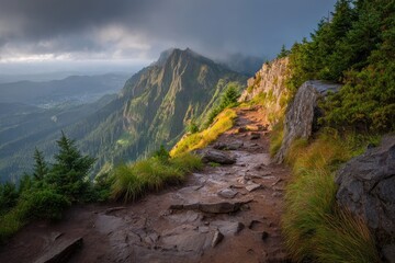 Mountain trail winding upward to summit, dramatic clouds above