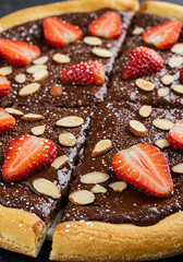 Sweet dessert pizza with chocolate spread, fresh strawberries, and almond slices