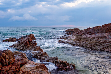 Obraz premium Rocky Coastline with Waves under Dramatic Cloudy Sky