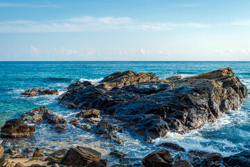 Rocky Coastal Shoreline with Waves under Clear Blue Sky