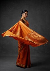 Elegant indian woman in a traditional orange silk sari with gold embroidery, posing gracefully