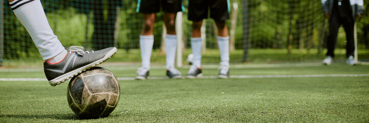 Header of teenage boys standing on outdoor soccer field, one Caucasian boy placing foot on soccer...