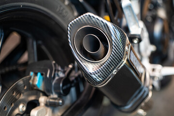 Close-up view of a motorcycle exhaust system and covered in sooty deposits. Black soot in tailpipe