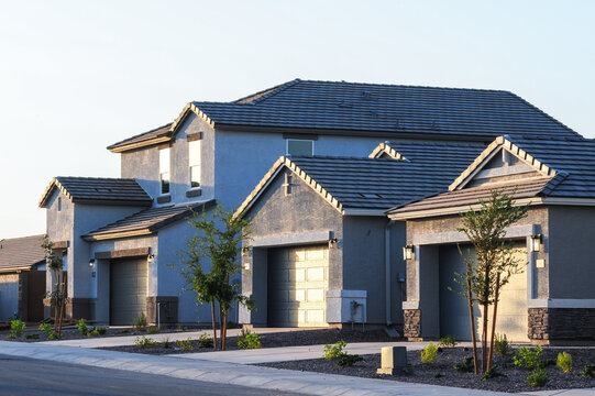 Newly built single-family homes with attached garages, fresh paint, and minimal landscaping, representing recent residential construction in a suburban housing development neighborhood