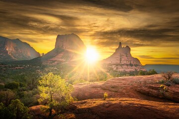 Scenic view of a sunset over Sedona's red rock formations with vibrant sky and lush greenery.